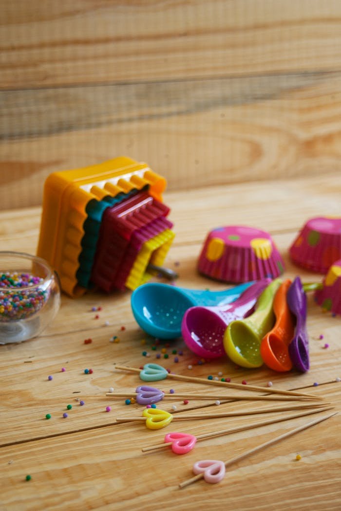 Vibrant baking cups and sprinkles on a rustic wooden table.
